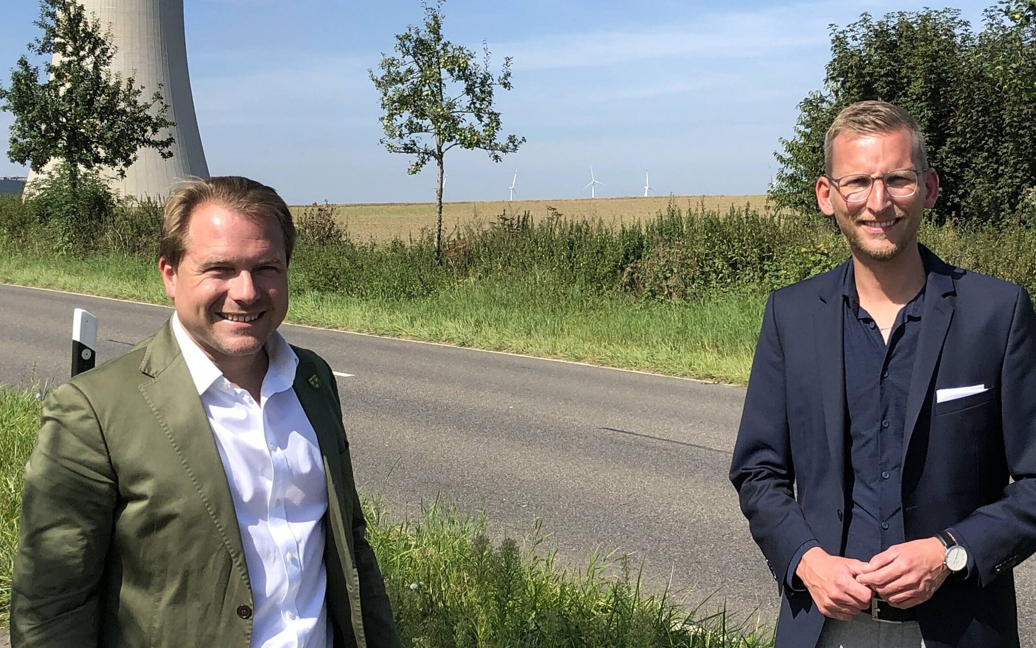  Martin Mertens und Daniel Rinkert mit der Fläche im Hintergrund, auf dem der Grundstein für neue Arbeitsplätze gelegt werden soll. 