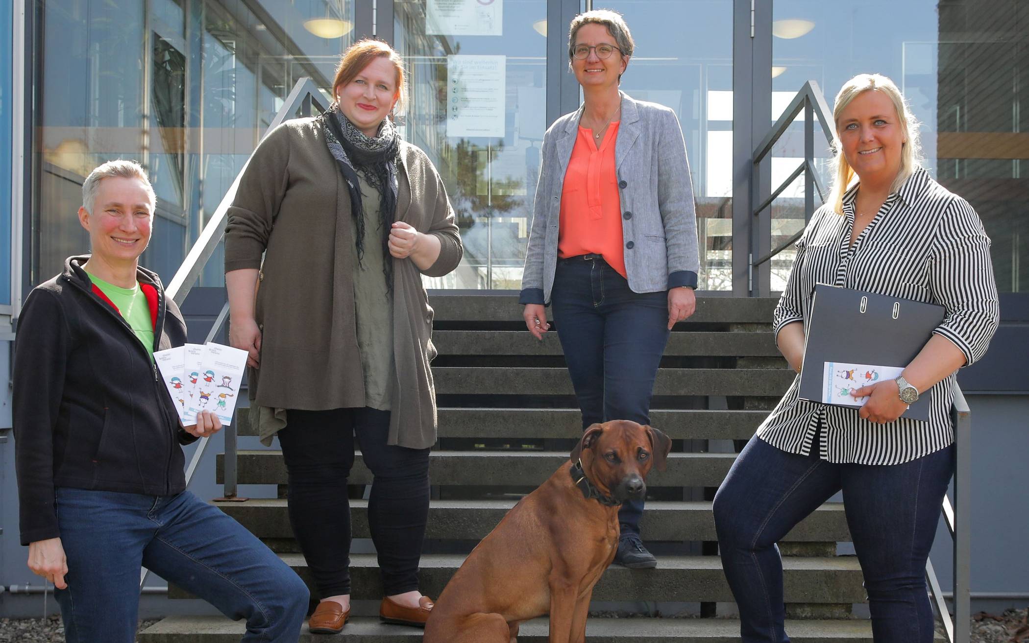  Lisa Fischer-Schreiber (Leiterin des Sprachtherapeutischen Dienstes) mit drei Team-Mitarbeitern und Therapiehund vor dem „Haus der Gesundheit“ in Grevenbroich. 