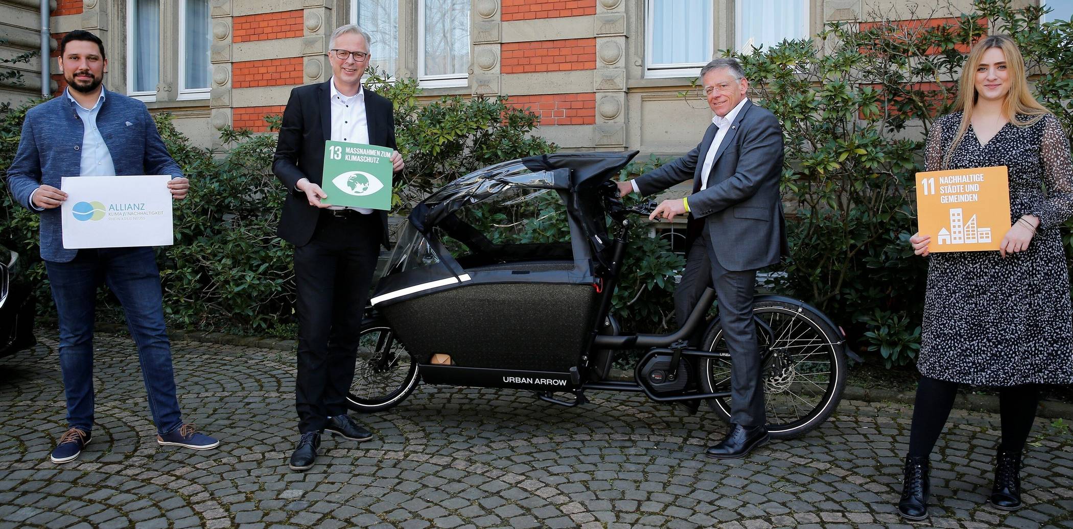  Vor dem Kreisständehaus in Grevenbroich präsentieren Landrat Hans-Jürgen Petrauschke (rechts), Kreisdirektor Dirk Brügge (Zweiter von links), Thiago de Carvalho Zakrzewski und Samira Smentkowski das neue e-Lastenrad beim Kreis. 