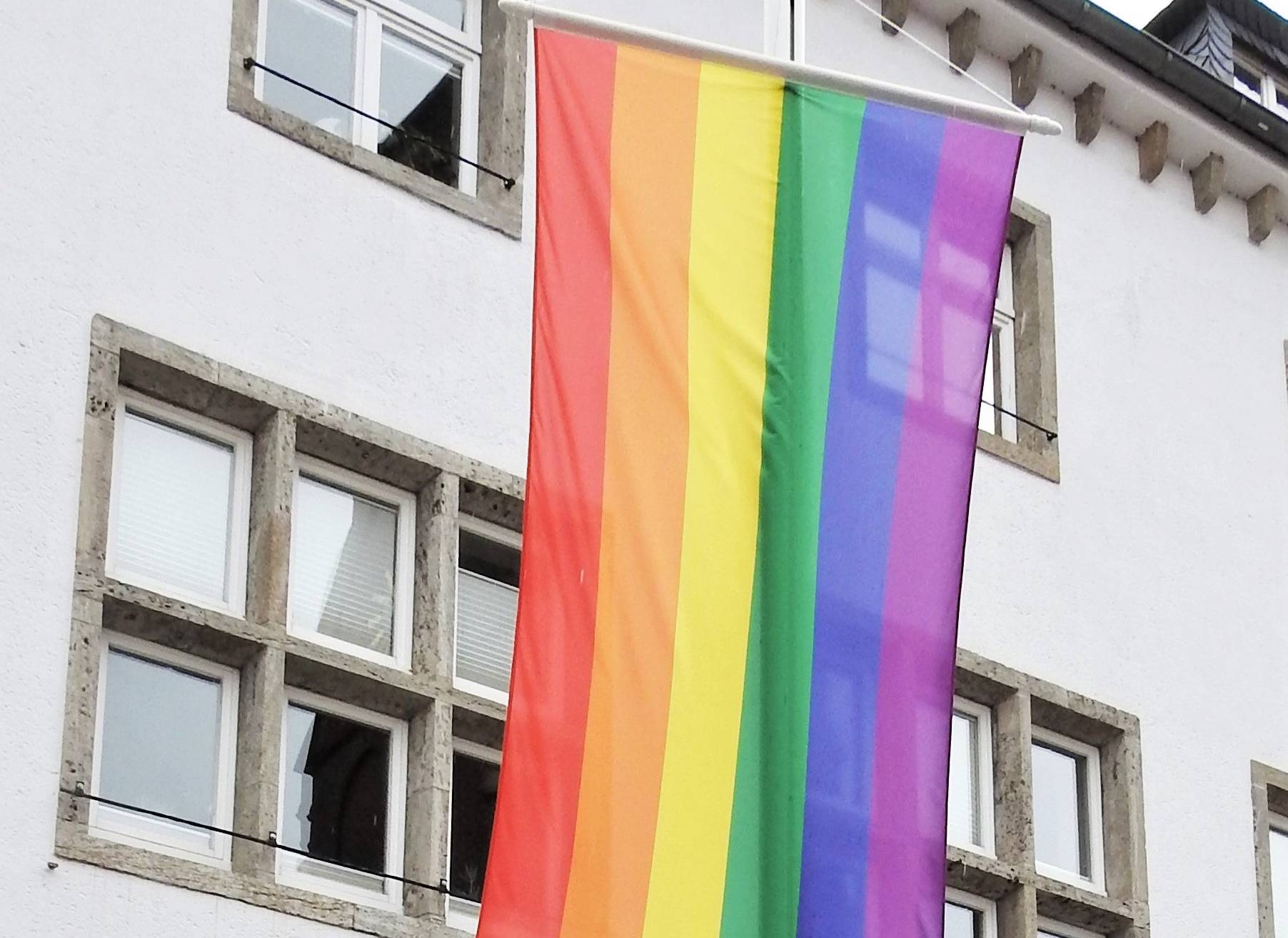  Bürgermeister Klaus Krützen vor der Regenbogen-Fahne am Grevenbroicher Rathaus. 