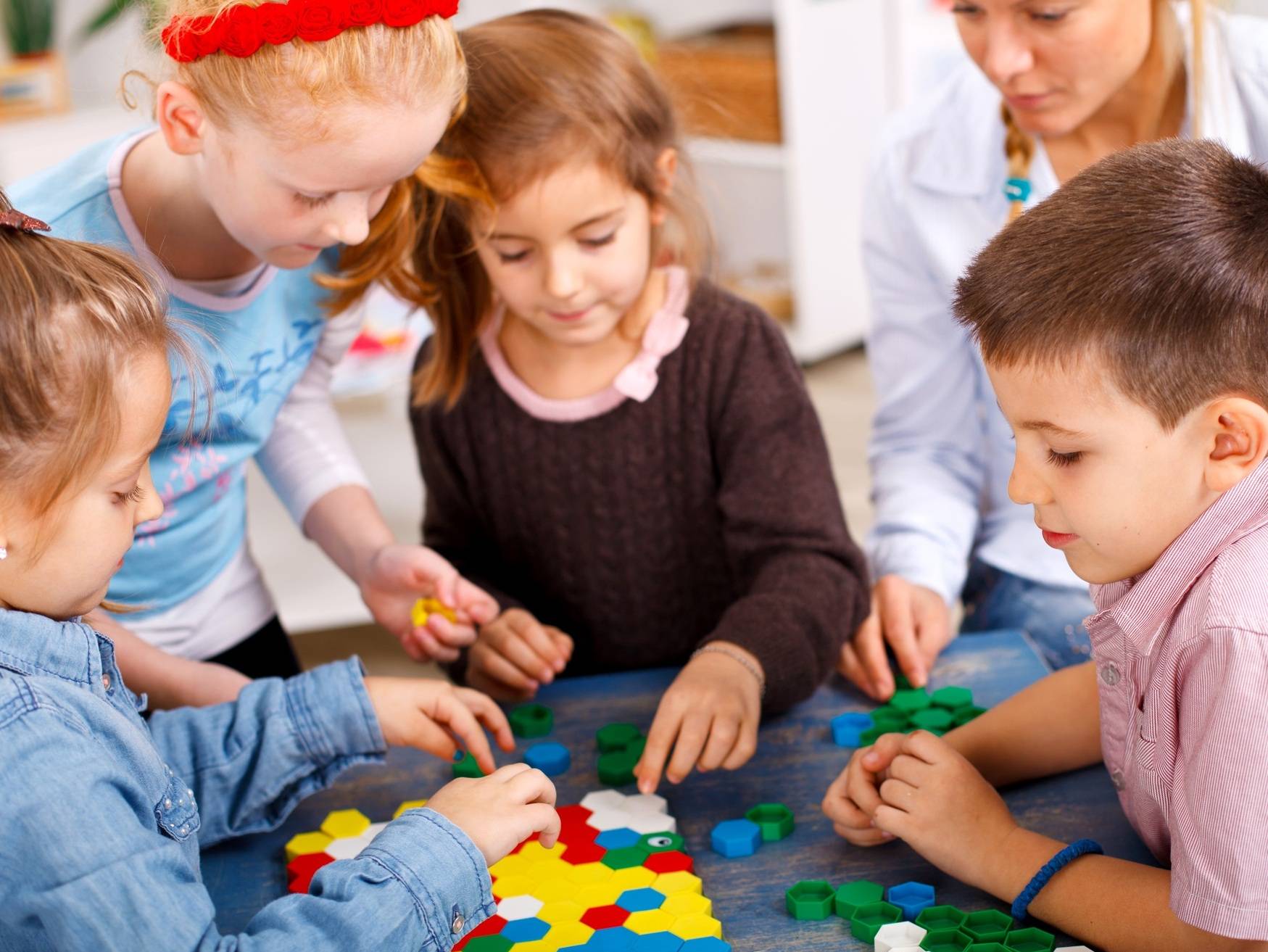  Teacher and children are playing a board game in the classroom 