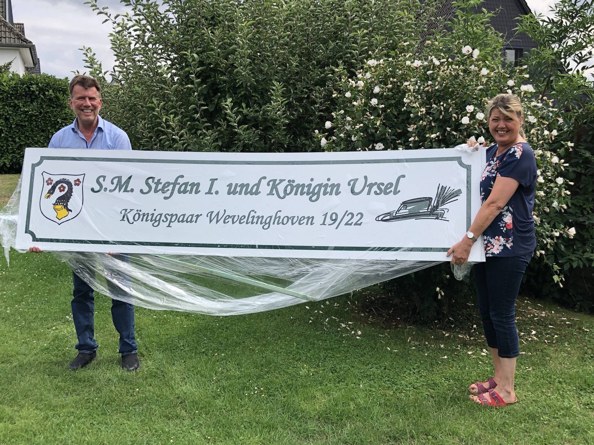  Stefan und Ursel Fücker präsentieren im Garten ihrer Residenz an der Grevenbroicher Straße die Tafel, die am Ende die königliche Residenz krönen soll. Der Zug biegt 50 Meter vor der Residenz übrigens nach rechts ab... 