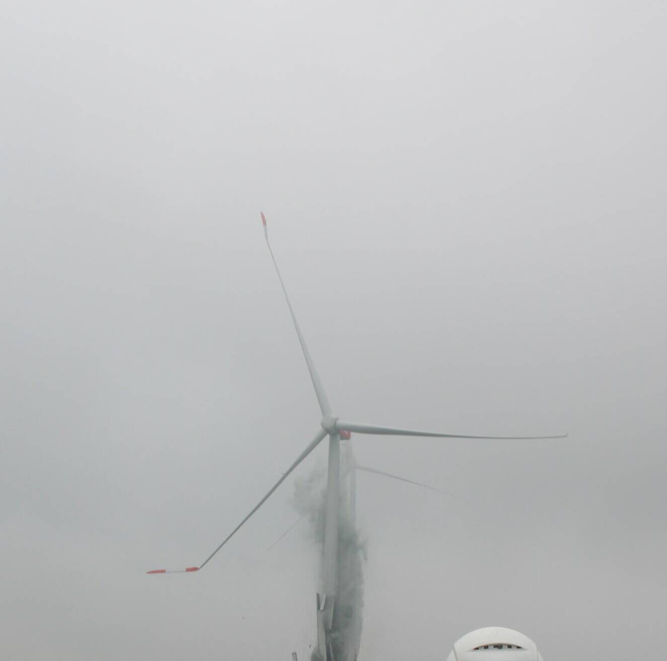 Das Windkraftrad sackt zusammen und fällt dann wie geplant in das vorbereitete Bett aus Sand und Kies. Die großen Rotorblätter biegen und brechen. Der Schrott muss nun geborgen und entsorgt werden. Immerhin geht es auch um giftige Stoffe.