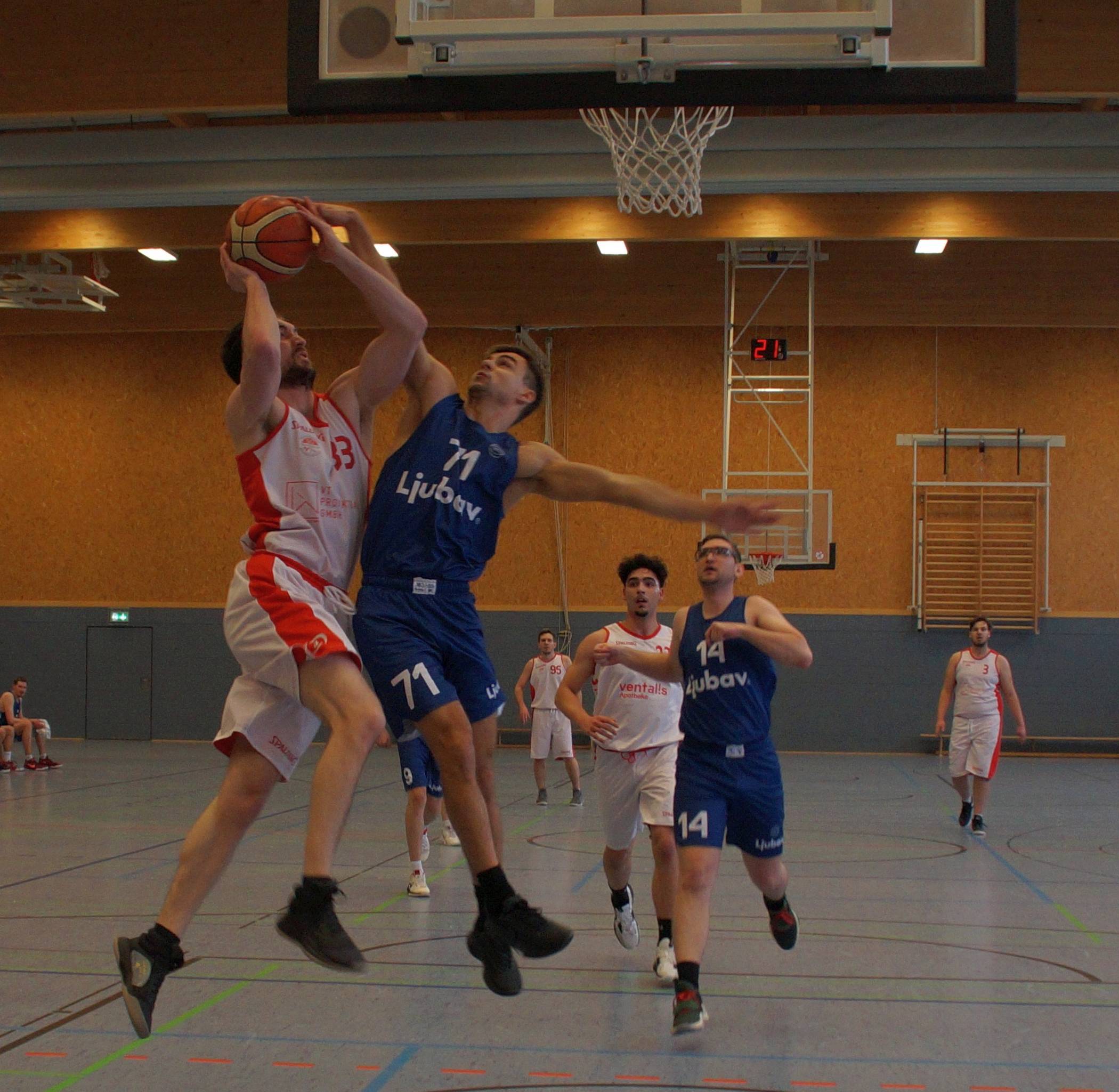  Der Gierather Nicolas Schlang (links, weißes Trikot, Nummer 33) wird von einem Spieler der TG Düsseldorf am Korberfolg gehindert. Im Hintergrund beobachten seine Mannschaftskamraden Aurélien Espinet, Samir Neumann und Niklas John (von links) die Szene. 
