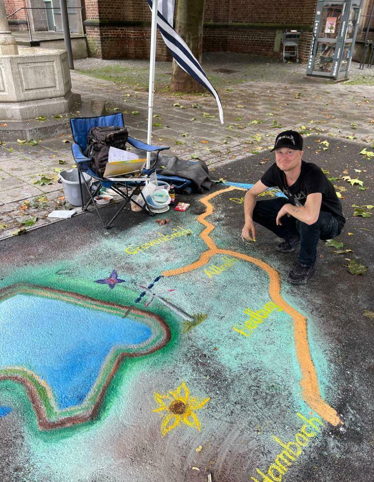  Hatte mit dem regnerischen Wetter zu kämpfen: Streetart Painter Patrick Schmitz, der während der Aktion den geplanten Tagebausee und die Rheinwasser-Transportleitung dorthin zeichnete. 