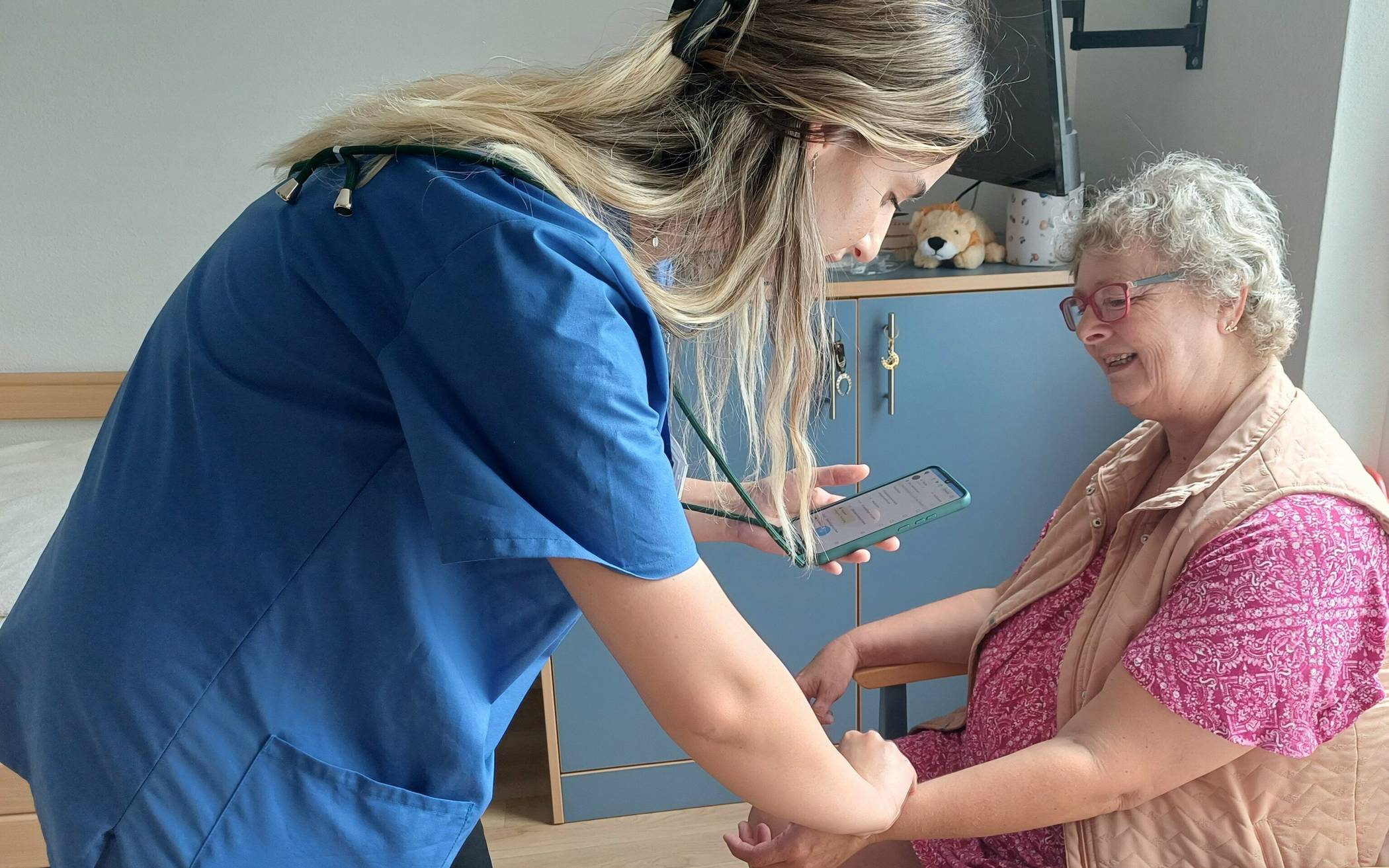 Dank der KI kann Pflegeassistentin Denada Doda Informationen wie beispielsweise die Pulsmessung von Bewohnerin Bettina Vieten schnell und einfach per Spracherkennung in das hausinterne Dokumentationssystem einpflegen.  