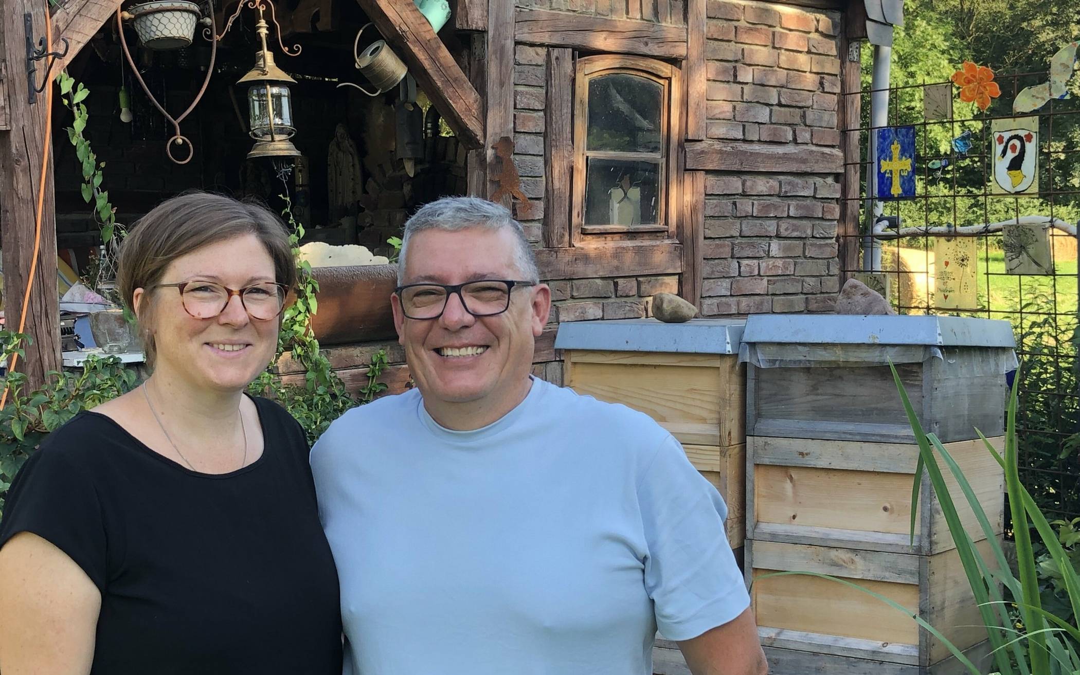 Miguel und Kathrin Coro im Garten ihres Hauses, in dem viele Jahre ihre Oma gelebt hat. Hinter ihnen die familieneigenen Bienenvölker. Im Hintergrund die selbst geplante, selbst gemauerte und selbst gezimmerte Outdoor-Küche mit Pizza-Ofen, großem Grill, durchdachtem Herd und einer großen Marien-Figur. Während Kathrin Coro die schnelle Alltagsküche übernimmt, kocht er die „Familien-Essen“. Zum Beispiel die „Gartenstadt-Paella“ – ohne Fisch oder Krustentiere, dafür mit Schweine- und Hähnchen-Fleisch.