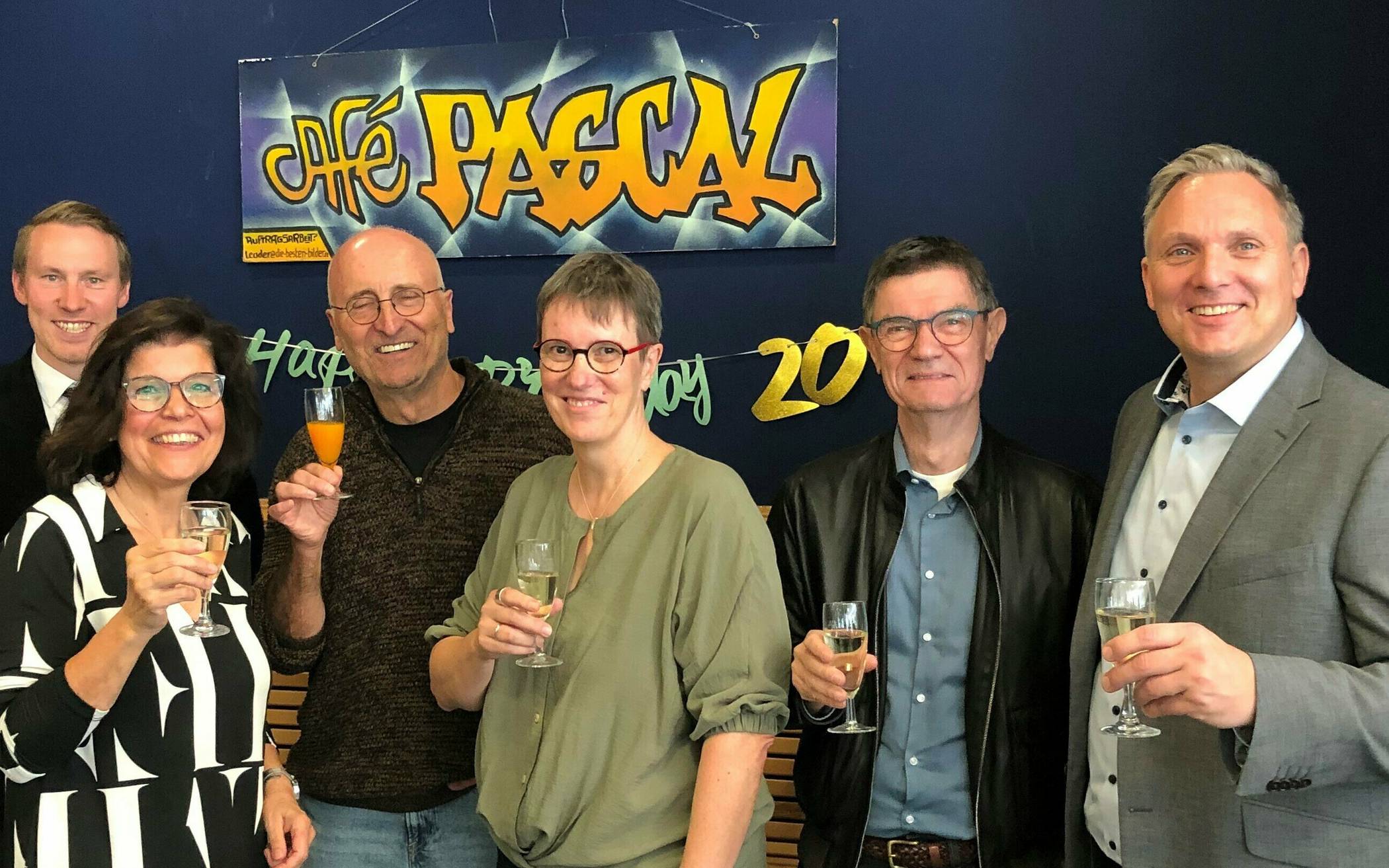  Ein Gläschen Sekt (alkoholfrei) auf den runden Geburtstag des „Café Pascal“ (von rechts): Schulleiter Gerhard Bodewein, sein Vorgänger Manfred Schauf (in seiner Ägide eröffnete das Café), Noch-Geschäftsführerin Bettina Sebestian, langjähriger Vorsitzender des Trägervereins Wolfgang Gsoll, langjährige „treue Seele“ Gabi Becker und Tim Gockel, der „Café Pascal e.V.“ als Vorsitzender anführt.  
