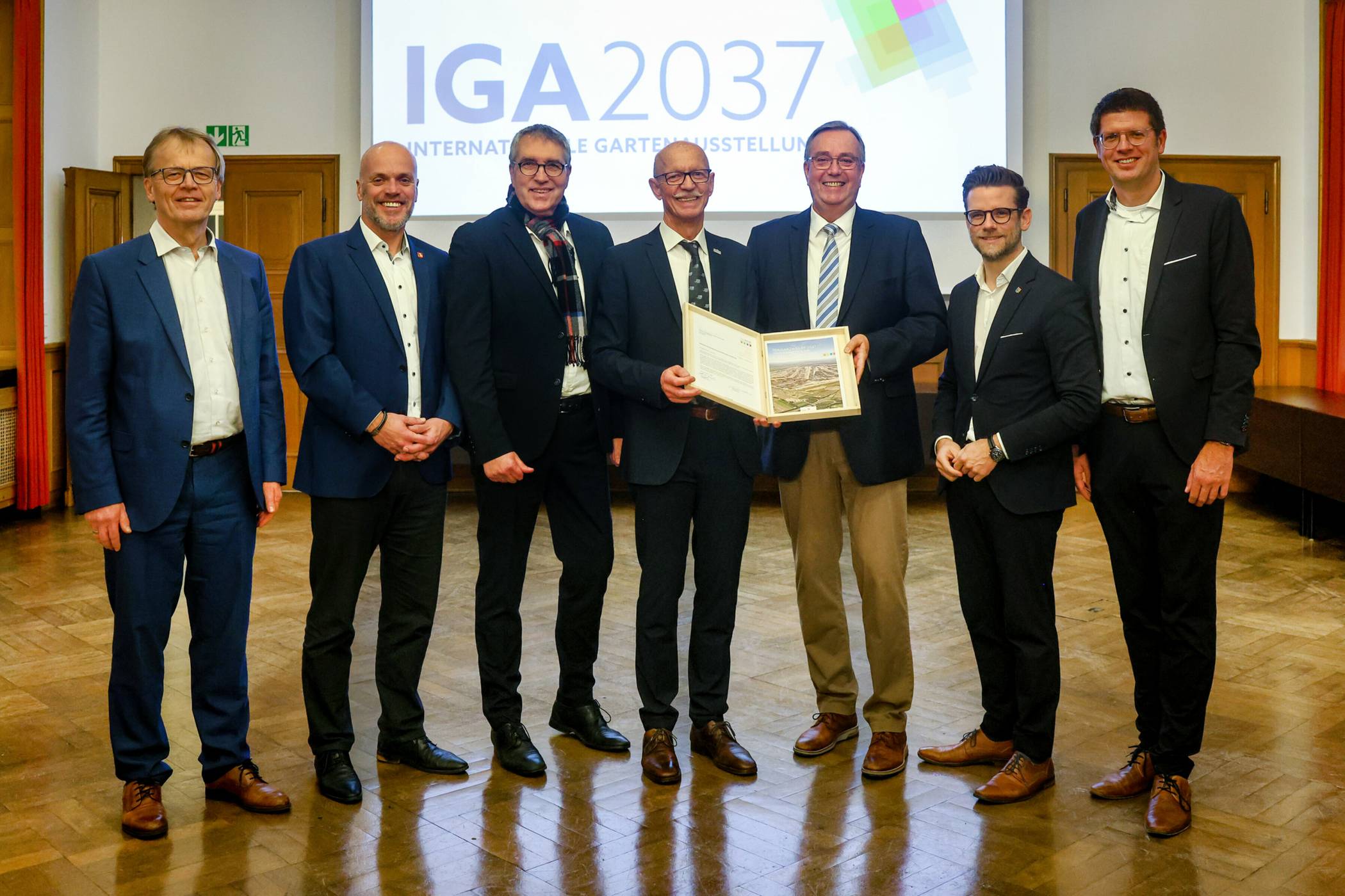  Der Zweckverband LANDFOLGE Garzweiler bewirbt sich bei der Deutschen Bundesgartenschau-Gesellschaft (DBG) um die Ausrichtung der IGA Garzweiler 2037. Die Übergabe der Bewerbung an den Vorsitzenden der Gesellschafterversammlung der DBG Hajo Hinrichs (3. von rechts) fand durch den Verbandsvorsteher und Bürgermeister von Jüchen Harald Zillikens (Mitte) bei einem Empfang im Rathaus Abtei in Mönchengladbach statt. An dem Empfang nahmen als Vertreter der Mitglieder des Zweckverbands zudem unter anderem (von rechts) der Bürgermeister von Erkelenz Stephan Muckel, Mönchengladbachs Oberbürgermeister Felix Heinrichs, der Bürgermeister der Landgemeinde Titz Jürgen Frantzen, Klaus Krützen als Bürgermeister von Grevenbroich sowie Michael Eyll-Vetter, Leiter der Sparte Entwicklung Braunkohle bei RWE, teil.   