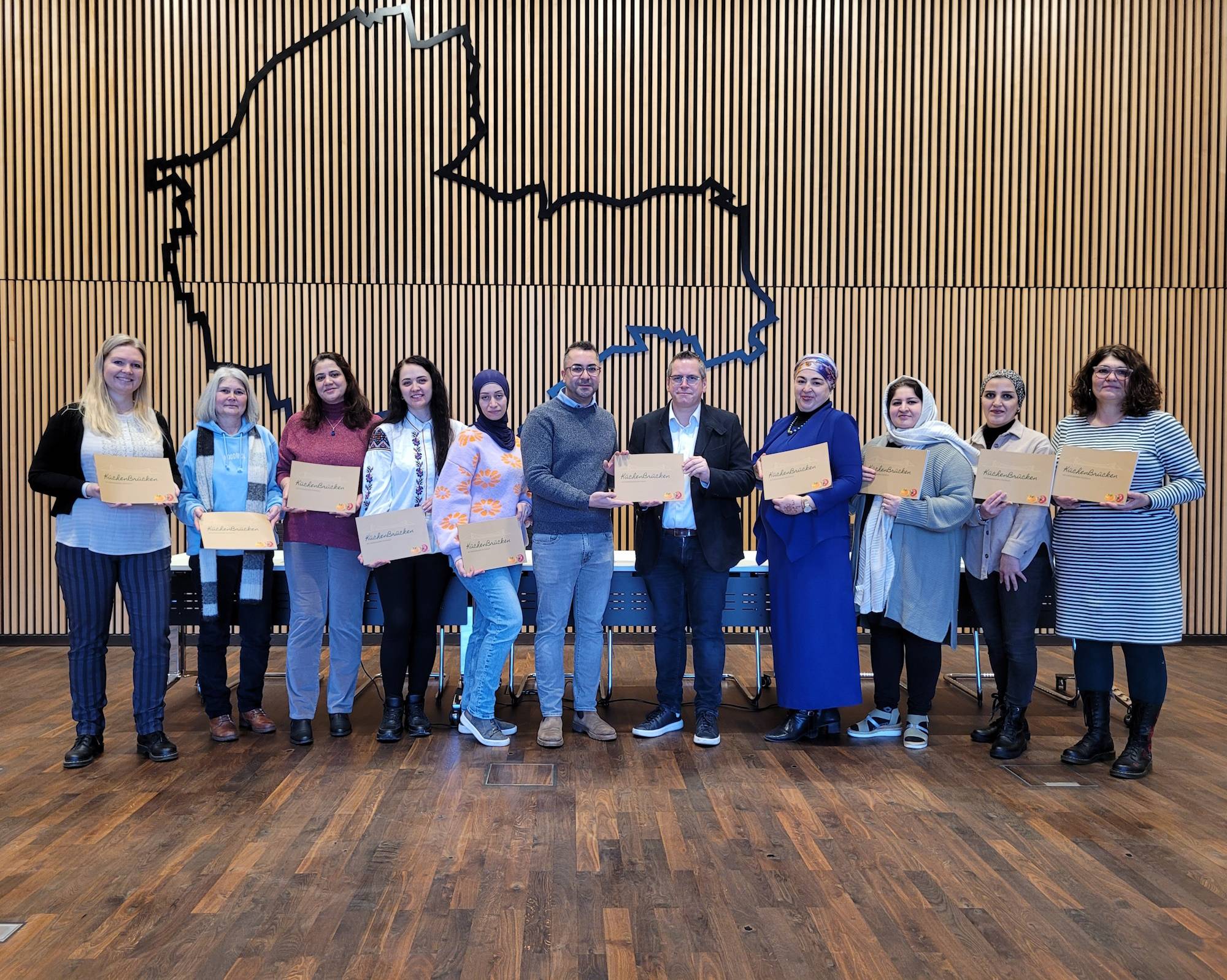  Initiator Bassel Essa (mitte) überreichte das interkulturelle Kochbuch gemeinsam mit sieben Köchinnen sowie Bärbel Vomland (rechts) und Anna Noddeland (links) von der Stadt Bedburg an Bürgermeister Sascha Solbach. 