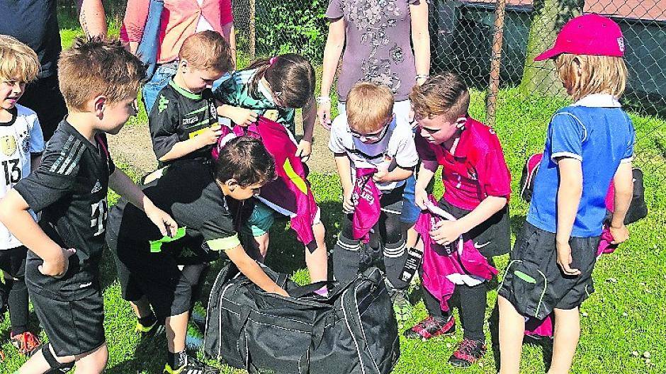  Landrat Petrauschke brachte den Kindern die Trikots, die von der Familienkarte gesponsert werden. Die Freude war groß, als die Bambini die Tasche auspackten (Foto rechts). 