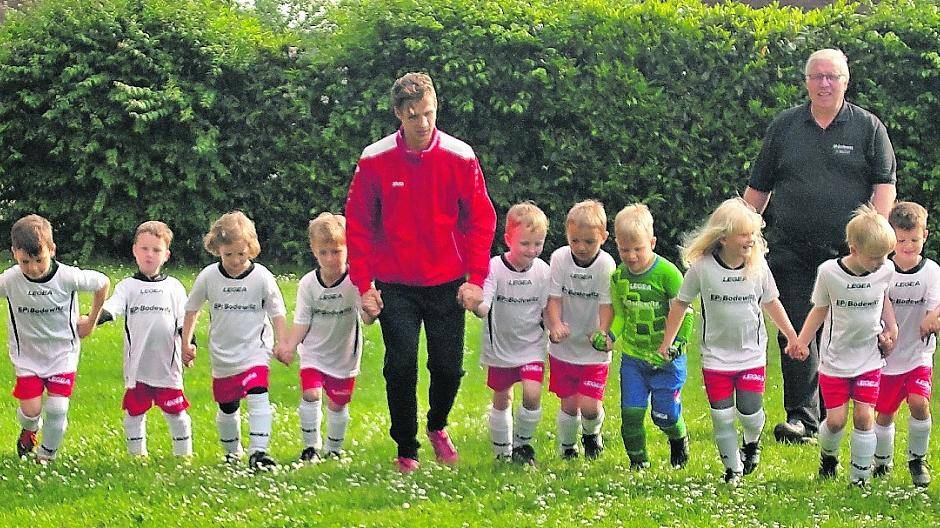  Die kleinen Kicker der „Rheinwacht“ aus Stürzelberg sind bereit für den ersten Aufgalopp in den nagelneuen Schweizer Trikots. Und das sehr zur Freude von Sponsor Jürgen Müller von „EP: Bodewitz“ (im Hintergrund in Schwarz).  