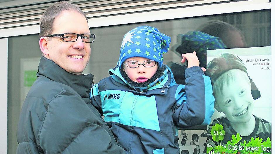  Keno auf Papas Arm vor Kenos Plakat, das in mehreren Schaufenstern in der Grevenbroicher Innenstadt zu sehen ist. 