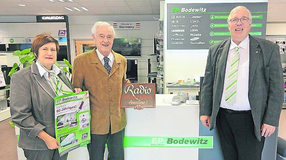  Der Senior-Chef mit dem Schild, mit dem einst alles begonnen hat. Mit ihm freuen sich Gerlinde und Jürgen Müller. 