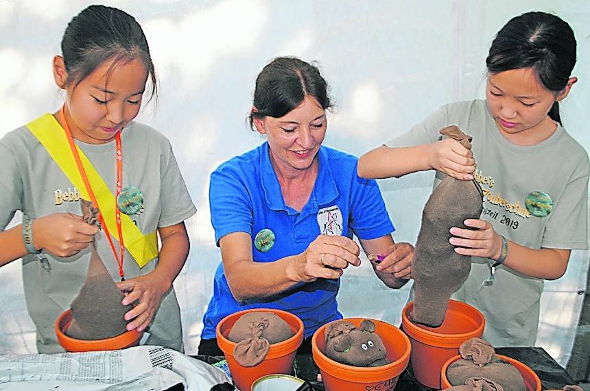  Betreuerin Monika bastelt mit den Kids Alraunen. Dazu wird Blumenerde in Nylonstrümpfe gewickelt und mit Kresse besät. 