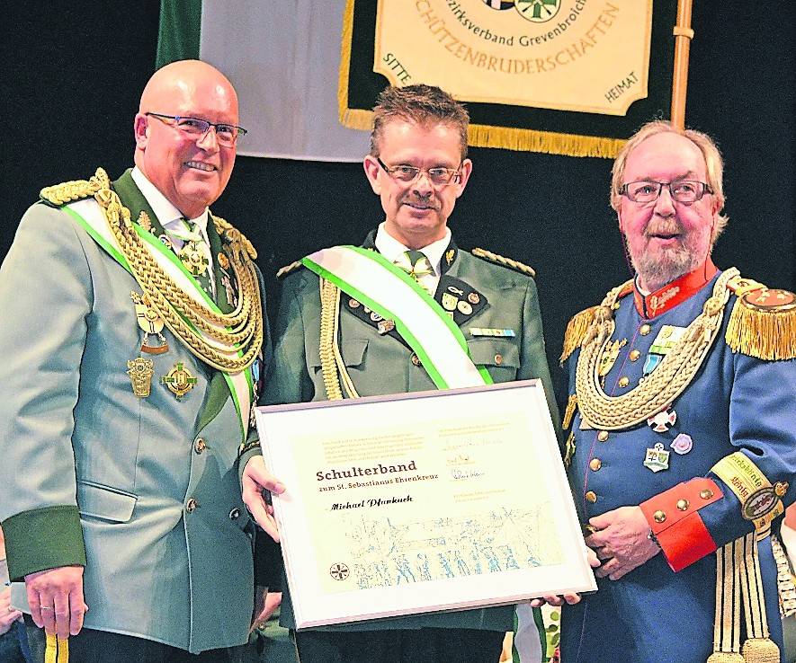 Michael Pfankuch (Bildmitte), der stellvertretende Bundesmeister des Bezirksverbandes Grevenbroich und Geschäftsführer des Diözesanverbandes Köln, wurde im Rahmen des Bezirkskönigsehrenabends jetzt von Diözesanbundesmeister Wolfgang Kuck (rechts) und seinem Stellvertreter Robert Hoppe (links) unter dem lang anhaltenden Applaus der zahlreich anwesenden Gäste mit dem Schulterband zum „St. Sebastianus“-Ehrenkreuz ausgezeichnet. <![CDATA[]]>